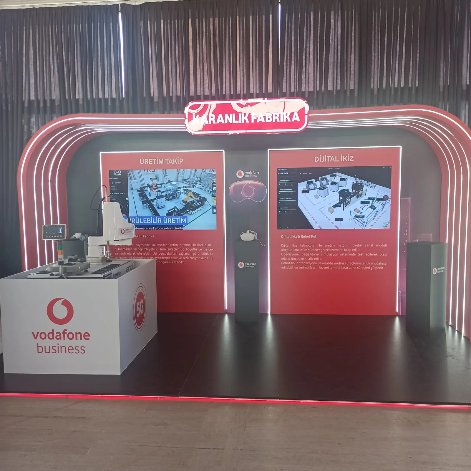 Vodafone Business “Dark Factory” stand — production tracking and digital twin screens, VR headset and robot arm
